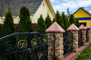Wrought iron fence with stone posts. Fence of the private house.