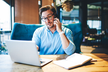 Professional executive manager discussing business plan on mobile while checking online documents.