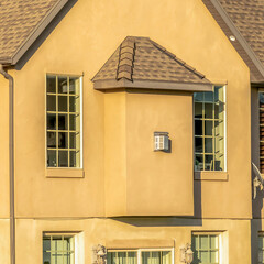 Square Home with dark roof shingles concrete brown wall and cottage pane windows