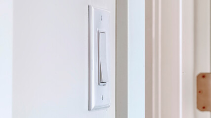 Panorama crop Side view of electrical rocker light switch mounted on white interior wall