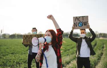 Group of young activists with placards standing outdoors by oil refinery, protesting.