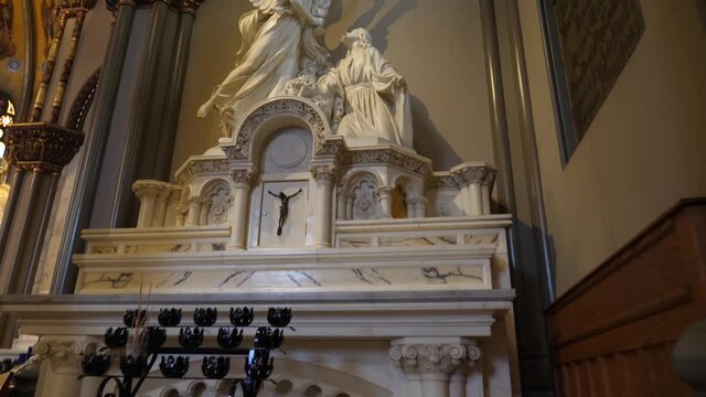 Marble angel statues in front of the altar rails for votive or prayer candles. St. Vincent De Paul Parish Church. Revealing tilting up shot.