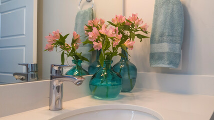Panorama Sink and stainless steel faucet on white countertop with flowers on vases