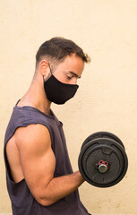 Chico joven entrenando en casa con mascarilla
