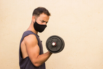 Chico joven entrenando en casa con mascarilla