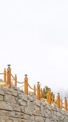 Obraz premium Vertical Rope fence with lamps on posts lining a retaining wall made of stone blocks