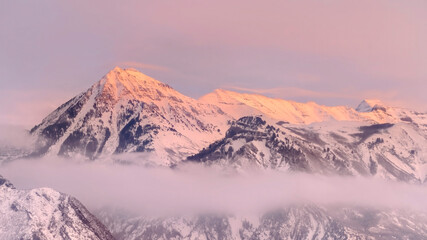 Panorama frame Snowy Wasatch Mountains with sharp peaks illuminated by sunset in winter