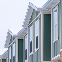 Square frame Vertical siding and stone brick wall at the townhomes upper storey against sky
