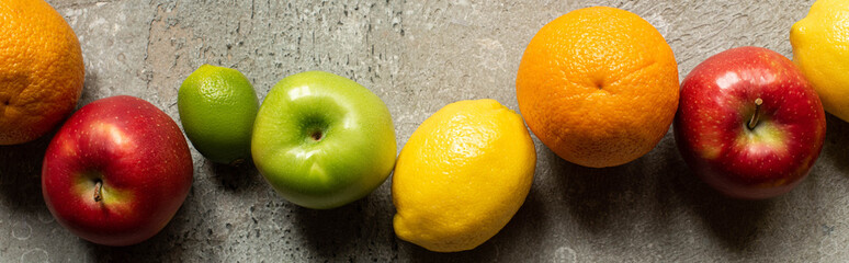 top view of tasty colorful fruits on grey concrete surface, panoramic shot