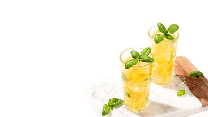 Citrus lemonade or mojito cocktail with lemon and orange and basil. Cold beverage or drink with ice on marble cutting board