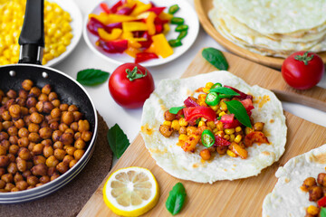 Vegan tortilla tacos with chickpeas, bell peppers, corn, tomatoes, basil leaves and green chilli....