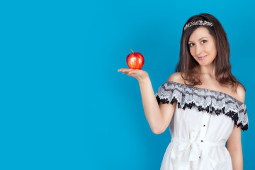 Young beautiful girl with dark hair, bare shoulders and neck, holding big red apple to enjoy the taste and are dieting, healthy eating and organic foods, feeling temptation, smile. Isolate. Copy space