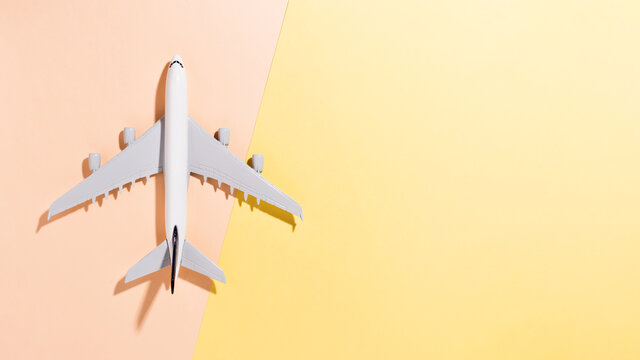 Model airplane on light yellow and orange color paper background. Flat lay, top view and copy space for your text