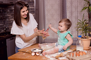 Happy family, mom, daughter play and cook in the kitchen, knead the dough and bake cookies