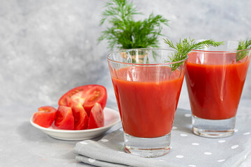 Tomato juice in glass cups. On a light gray background. Vitamin drink. Garnished with sprigs of dill.