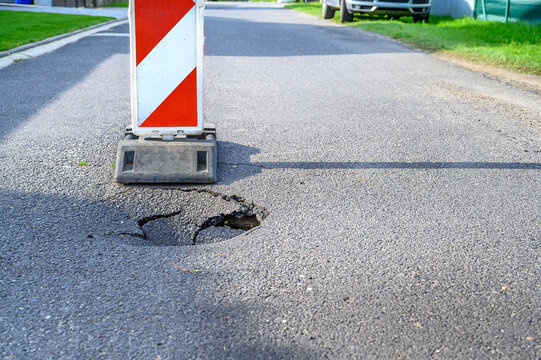 Pothole on asphalt street with detour alert traffic sign