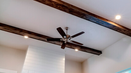 Panorama frame Ceiling fan with lights flanked by decorative wood beams and recessed lighting