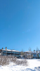 Fototapeta na wymiar Vertical Houses on snowy hill terrain in Park City Utah with clear blue sky background