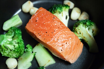 Cooking salmon steak on pan with broccoli and garlic. Grill salmon fillet.