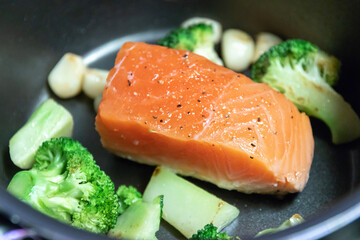 Cooking salmon steak on pan with broccoli and garlic. Grill salmon fillet.