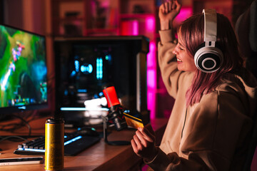 Image of girl holding credit card and playing video game on computer