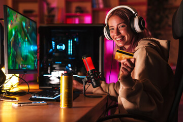 Image of girl holding credit card and playing video game on computer