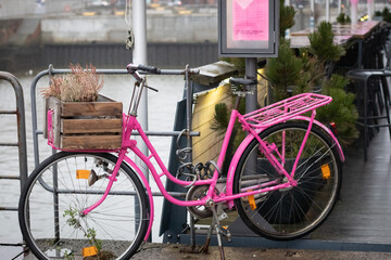 Retro urban Bicycle with a basket leaning against a fence on a sidewalk with a river in the background. A bicycle of a rental sharing service.