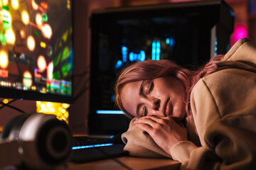 Image of exhausted girl sleeping on table while playing video game