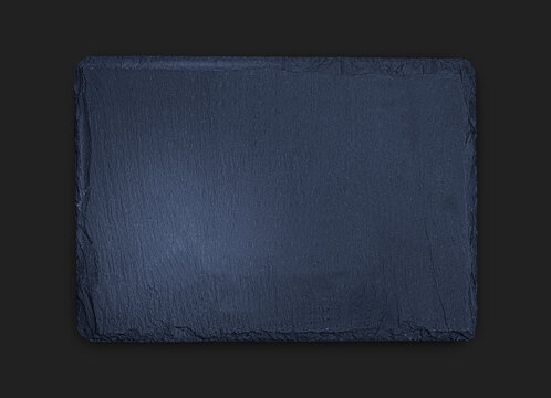 Gray slate board on black wooden table close up photo, natural texture with copy space