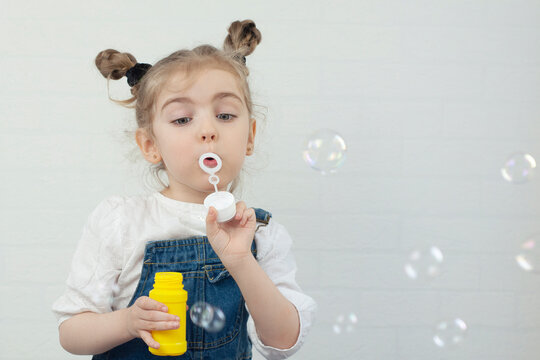A small child blows soap bubbles. Girl is happy