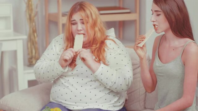 Close up. Bulimic and overweight girl trying bread rolls. Doctor talking about weight problem and consults about health issues with her friend girls. Healthy food concept. Tinted video. Prores 422. 