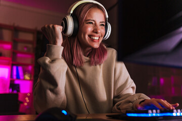 Image of girl making winner gesture and playing video game on computer