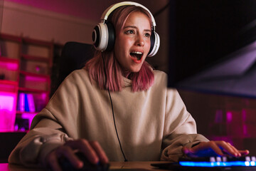 Image of shocked girl in headphones playing video game on computer