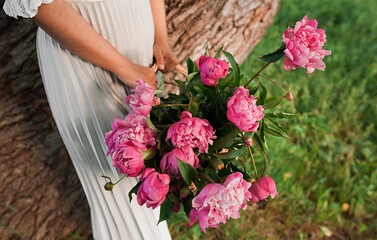 Wonderful bouquet of pink flowers. The bride is holding a basket with beautiful fresh peonies. 