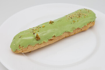 Pistachio Eclair on a White Plate with a White Background