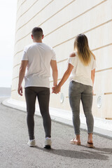 Young Spanish couple in love strolling hand in hand with love