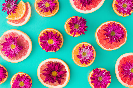 Pattern Made Of Slices Of Citrus Fruits (orange, Grapefruit) With Purple Flowers  In A Turquoise Background