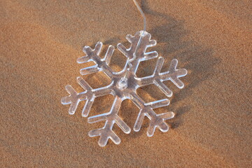 Transparent snowflake in desert sand dune. Merry Christmas/Christmas/Happy Holidays/Season's Greetings/Happy New Year/festive/desert/sand dune/celebration concept/background/theme.