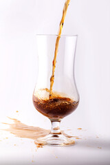 Glass with carbonated drink of dark color and foam.
