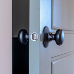Square frame Partially opened home bedroom hinged wooden gray door with black door knob