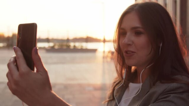 Young attractive business woman sitting outdoor on the bench. Sunset light.