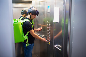 Food delivery concept. The food delivery man goes up in the elevator to find the apartment that placed the order.