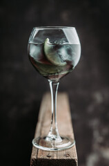 Black cocktail with lime slices in wine glass on the rustic background. Selective focus. Shallow depth of field.