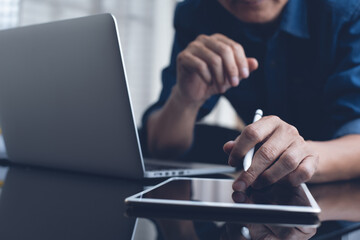 Casual man surfing the internet online working on laptop computer and using digital tablet at home office