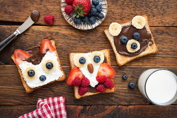 Kids breakfast funny toasts on wooden table. Food art ideas for children's breakfast or school lunch menu. Table top view