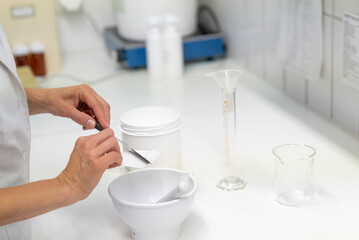 close up view of a pharmacist in the laboratory mixing a medical ointment in a bowl - obrazy, fototapety, plakaty