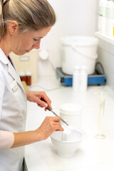 blonde female pharmacist perparing a medical ointment in the laboratory of the pharmacy