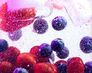 Close up view of the cold and fresh lemonade with bright berries and ice cubes in neon light....