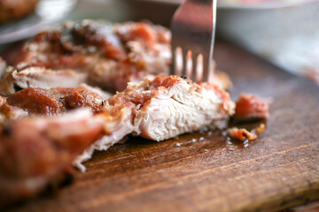 Grilled or fried chicken breast on the board cut with a fork. Selected focus.