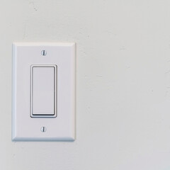 Square Electrical rocker light switch with flat broad lever on white interior wall